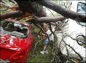 Cecelia Shaw makes he way through a tree-crushed car and a mobile house to check her friends and animals that were still inside in Parker, Florida