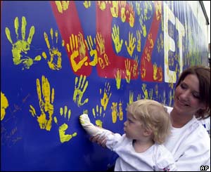 A Hungarian woman holds her daughter as she puts her hand print onto a side of a truck 
