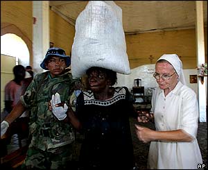 An Argentine UN soldier and a nun help a woman as she is carrying food during a distribution in Gonaives.
