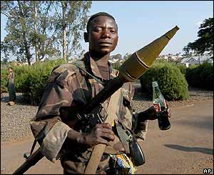 Rebel soldier holds rocket-propelled grenade launcher and a soft drink