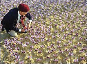 Raymond Daeche, from Harlow in Essex, plants a Union Jack flag in the sand on Sword Beach in Hermanville, Normandy 
