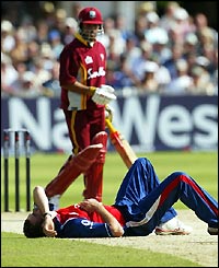 Jimmy Anderson lies prostrate on the ground as he watches the ball fly past him