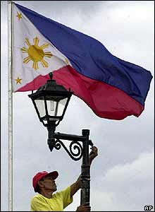 Worker puts fresh paint on a flag-pole in Rizal Park, Manila