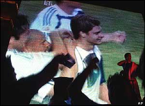 Greek fans react as Angelos Charisteas celebrates his goal on a video screen outside the Athens City Hall on Sunday