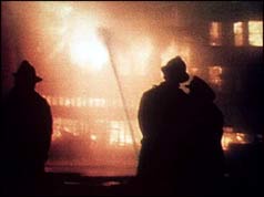 Silhouetted firefighters against blazing building