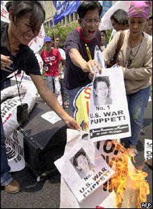 Protesters burn photographs of Philippine President Gloria Arroyo during a demonstration near the US embassy in Manila, 16 July 2004