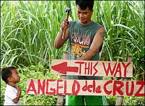 A relative of Angelo de la Cruz fixes a signboard in this farm village of Buenavista, north of Manila 20 July 2004