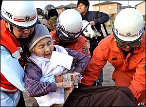 Elderly woman carried by rescue workers from a village at Nagaoka city in Niigata prefecture