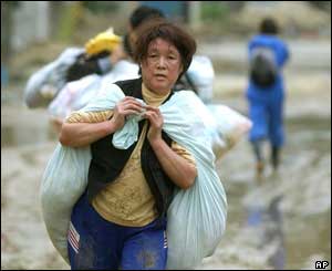 A woman carries a large load of belongings on her back in the muddy road in Ojiya, northwest of Tokyo, Monday, Oct. 25, 2004. 