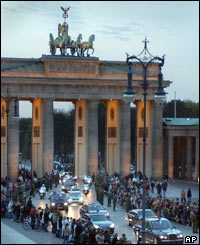 Police escort the Queen and the Duke of Edinburgh as they drive through Berlin's Brandenburg Gate
