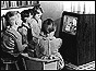 Children crowded round a black and white television