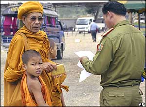 A police officer checks the papers of Buddhist monk Khampan Paimanee, 66, of Paxan province, Thursday, Nov. 25, 2004, 