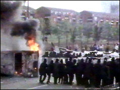 Police form a line next burning upturned car