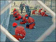Prisoners kneeling in front of guards at Camp X-Ray
