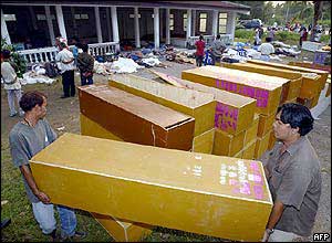 Rescue workers pile up coffins beside dead bodies at a cremation site in Khao Lak, a province of the tourist resort island of Phuket
