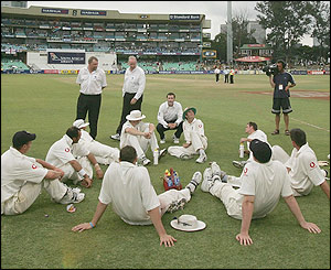 England's players wait on the field after bad light stops play