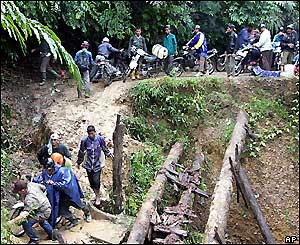 Refugees from Meubolah cross a damaged road in the jungle, 31 December 2004