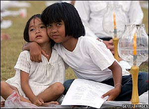 Two young Thai girls hug during a candlelit memorial service in Thailand
