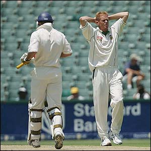 Shaun Pollock of South Africa holds his head in his hands as Andrew Strauss runs