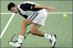 Henman bends down low to hit a winning volley over the net