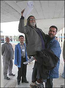 An elderly disabled man is carried to a polling station