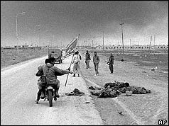 Iranian soldiers riding on a motorbike past bodies of Iraqis