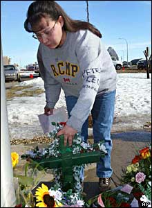 A woman puts flowers on a makeshift memorial for the men