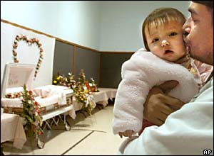 Rodney White holds his youngest daughter during the wake for older daughter Alicia Alberta White