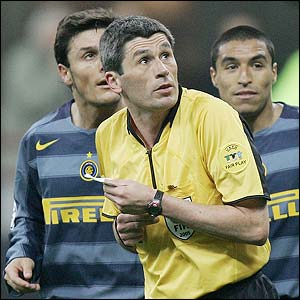 Referee Markus Merk takes evasive action as flares rain down at the San Siro