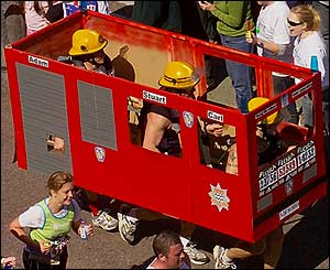 Three firemen carry their truck round the course