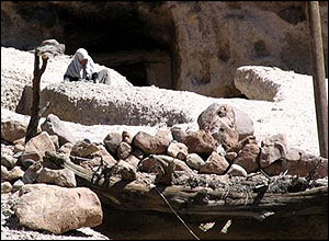 Woman works to shore up wall near her home in Maymand
