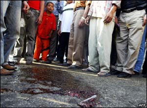 People gather around a pool of blood near where two Egyptian women opened fire on a tourist bus.