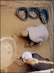 Egyptian labourers clear sand from the pit where the mummy was found