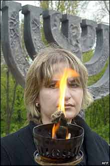 A woman holds a torch in front of the Minora monument at Babiy Yar square in Kiev, Ukraine