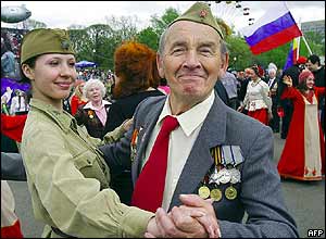 Girl in World War II uniform dances with old soldier