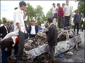 People stand on burned-out car, Andijan