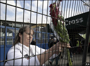 Tina Debenham attaches a floral tribute to the railing outside Kings Cross