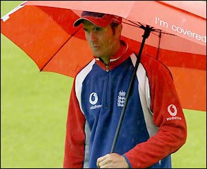 England captain Michael Vaughan shelters under an umbrella as the rain continues to fall