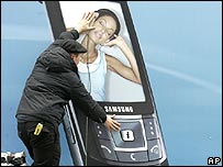 فردی در حال نصب آگهی تبليغاتی تلفن همراه در نمايشگاه سبيت