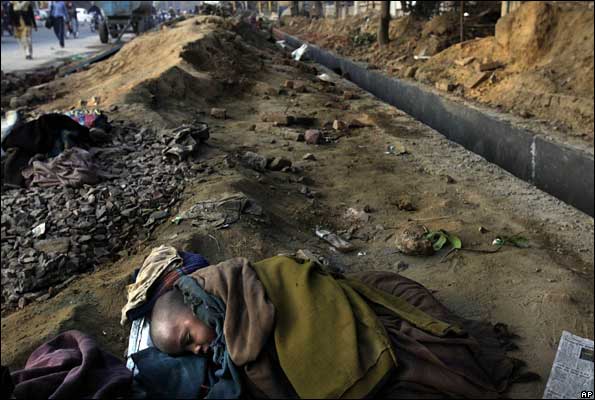 A child of a worker sleeps on a Delhi road near a Commonwealth Games site