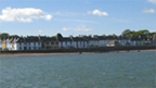 View across bay to Garlieston where a row of single and two-storey buildings line the promenade.