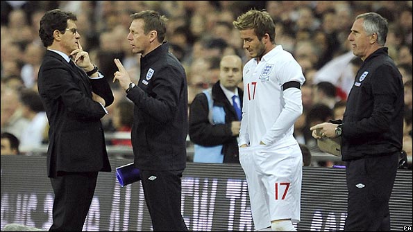 Fabio Capello chats with Stuart Pearce while David Beckham prepares to appear