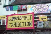Signs reading 'Goddess Temple' and 'Womanspirit Exhibition' are displayed outside the building