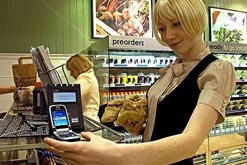 Woman using a mobile phone to pay in a sandwich shop, PA