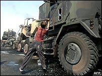 Menino iraquiano ao lado de veículos militares americanos