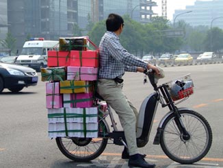 A man on a bike laden with parcels.