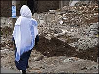 Woman walks past demolished house