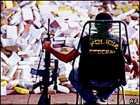 Policial em frente a carregamento de drogas apreendido