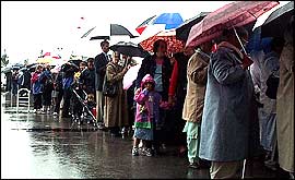 People queue in the rain to see the queen