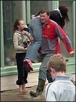 A man carrying a woman through a flooded street